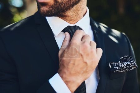I make sure I look good. an unrecognizable man adjusting his tie outside