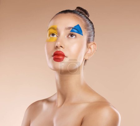 Photo for Makeup, clown and young woman with facial art, natural beauty and wellness with brown studio background. Artist, female and girl being creative, with pride and confident with cosmetics or face paint - Royalty Free Image