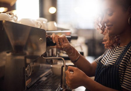 Foto de Ella sabe cómo preparar la mezcla perfecta. Primer plano de un barista operando una máquina de café en un café - Imagen libre de derechos