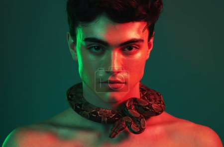 Snake, beauty and man in studio with green mock up with cosmetics, skincare and lights aesthetic for creative, art and animal print. Neon creativity, natural and nature pet fearless model on mockup.
