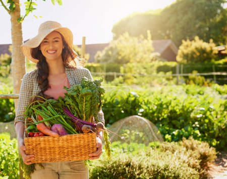 Nichts genetisch verändertes an diesen Gemüsesorten. Porträt einer jungen Frau, die einen Korb mit frisch gepflückten Produkten in einem Garten trägt