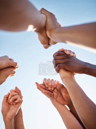 Photo for Low angle, group and holding hands in support, trust huddle and motivation for global success, volunteer community or diversity. People, friends or teamwork collaboration in circle for climate change. - Royalty Free Image