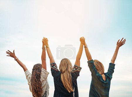 Photo for Forget all your worries for a moment. Rear view shot of a group of friends standing with their arms outstretched outside - Royalty Free Image