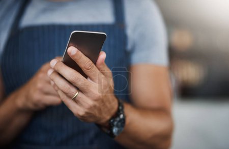 Photo for Barista apps are now a thing. a man using a mobile phone while working at a coffee shop - Royalty Free Image