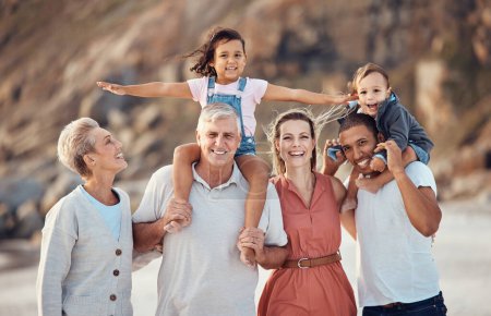 Foto de Retrato de playa familiar, niño al hombro y papá, mamá y abuelos multiculturales juntos de vacaciones. Familia grande feliz, sonrisa de generación con felicidad al aire libre en vacaciones de verano para la diversidad. - Imagen libre de derechos
