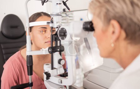 Eye exam, ophthalmologist and vision of woman, eyes or eye test with slit lamp or machine. Healthcare, eyesight and medical examination by doctor or optometrist at hospital or clinic for wellness