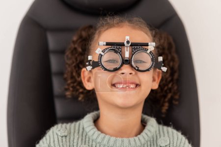 Trial frame, vision and eye test of girl at hospital or optometry clinic for eyewear, health and eye wellness. Exam, glasses and child testing eyesight for new optical lenses, frames or spectacles