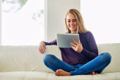 She loves spending time online. Full length shot of an attractive young woman using her tablet while chilling at home Poster #620166678