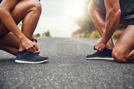 Téléchargez les photos : Sécuriser nos chaussures avant une course. un couple méconnaissable s'entraînant pour un marathon en plein air - en image libre de droit