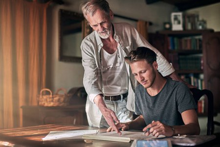 Foto de Mantener sus negocios en la familia. un padre y su hijo trabajando en un diseño para su negocio familiar en casa - Imagen libre de derechos