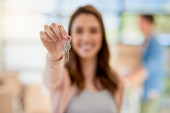 The key to unlock a new life. Portrait of a young woman holding up the keys to a new home with her boyfriend in the background Stickers #620278128