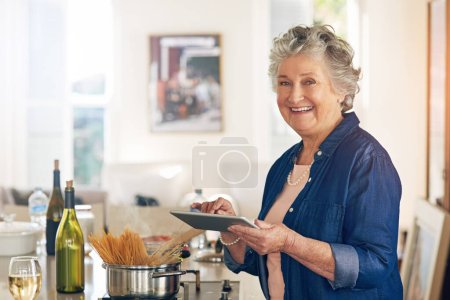 Photo for It smells so delicious in here. Portrait of a senior woman using a digital tablet while cooking in her kitchen - Royalty Free Image