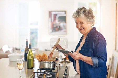 Photo for This recipe is so easy to follow. a senior woman using a digital tablet while cooking in her kitchen - Royalty Free Image