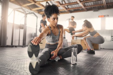 Photo for Stretching, fitness and training with black woman in gym with water bottle for exercise, sports and workout. Health, wellness and energy with girl and legs warm up for performance, muscle and strong. - Royalty Free Image