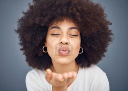 Photo for Kissing, love and romance with a black woman blowing a kiss in studio on a gray background for romantic affection. Beauty, lips and flirt with an attractive young female making a mouth gesture. - Royalty Free Image