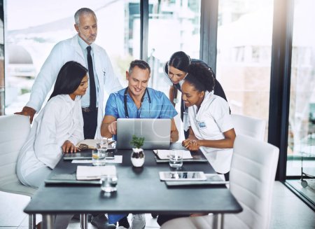 Photo for Meeting to discuss best practices. a group of medical professionals gathered around a laptop in the boardroom - Royalty Free Image