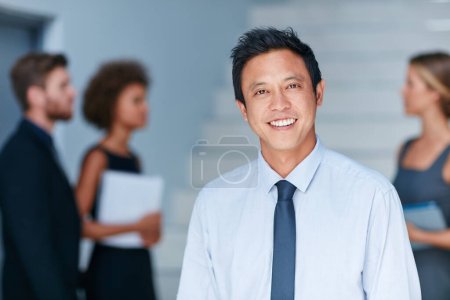 Always keep a clear vision of your goals. Portrait of a young businessman standing in an office with colleagues in the background