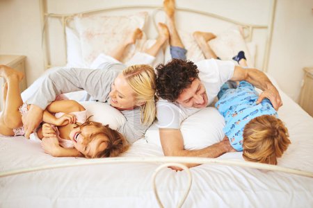 Foto de Ataque de cosquillas. una familia divirtiéndose juntos por la mañana en casa - Imagen libre de derechos
