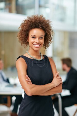Photo for Shes built her career on being positive. Portrait of a smiling young businesswoman standing with her arms crossed in a modern office - Royalty Free Image