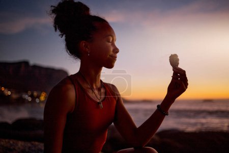 Foto de Meditación en la playa, puesta del sol y yoga mujer con humo de aromaterapia salvia para la curación de aura, alma o chakra energía. La mentalidad zen, pilates mindfulness y chica negra meditan para el equilibrio espiritual crepuscular. - Imagen libre de derechos