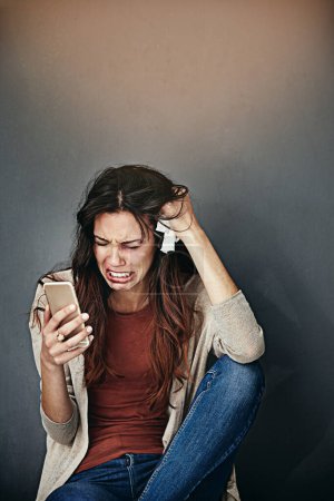 Foto de Hay que hacer algo. una joven golpeada y magullada llorando mientras mira su celular - Imagen libre de derechos