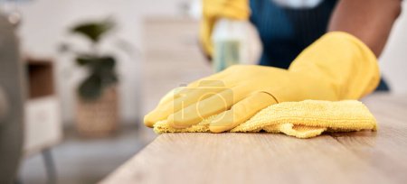 Foto de La limpieza, la tela y las manos de un hombre en una mesa de limpieza del polvo con guantes en una casa. Bacterias, servicio y limpiador con producto a limpiar para la desinfección de una superficie, escritorio o apartamento para la salud. - Imagen libre de derechos
