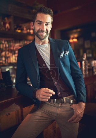 Pull up a chair. Cropped portrait of a young man standing in a bar