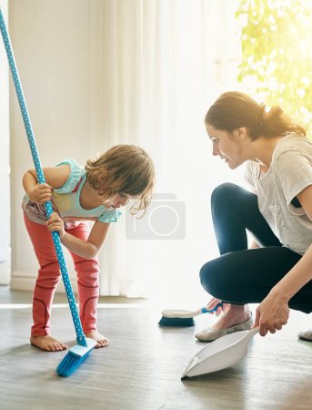 She knows to clean up her mess. a mother and daughter sweeping the floor together