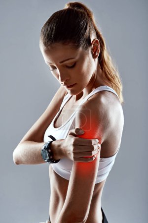 Se lastimó el brazo. Foto de estudio de una joven atlética sosteniendo su brazo con dolor sobre un fondo gris