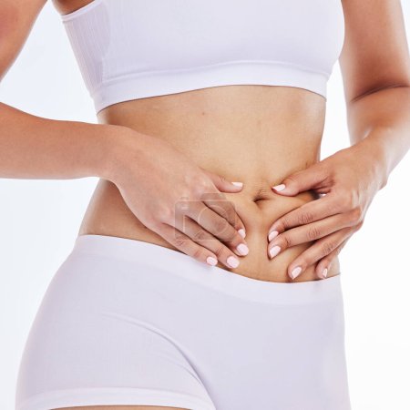 Stomach, tummy tuck and woman hands on body for diet, fitness and gut health promotion on a studio white background for sports, wellness and workout. Healthy, natural and detox girl abdomen progress.