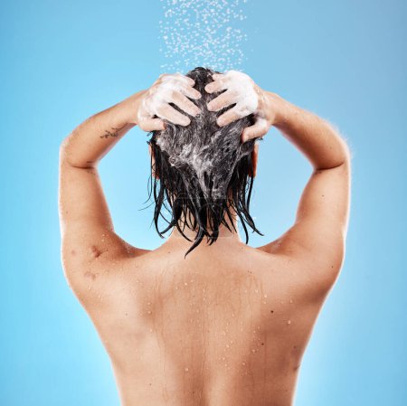 Foto de Ducha, cabello y champú con una mujer limpiando con agua para el cuidado del cabello en el estudio sobre un fondo azul. Higiene, agua y limpieza con un lavado femenino para tratamiento o hidratación en el baño. - Imagen libre de derechos