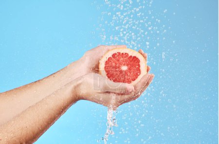 Grapefruit in hands, water splash and studio background for healthy, vegan and wellness food on advertising, marketing or promotion mockup. Detox, vitamin c and juice fruit benefits in clean skincare.
