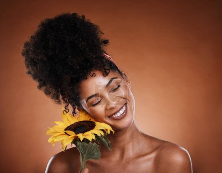 Sunflower, beauty and black woman in studio for skincare glow, wellness and cosmetics benefits with promotion, marketing and advertising space. Young model with natural flower for hair and skin care.