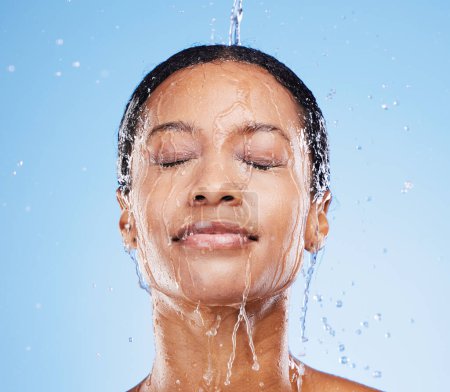 Foto de Mujer, ducha y agua en hidratación facial para una higiene limpia y fresca sobre fondo azul estudio. Mujer en lavado de belleza sanitaria para cuidado de la piel, limpieza y bienestar o tratamiento de limpieza natural. - Imagen libre de derechos