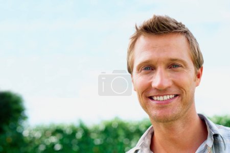 Photo for Closeup of a handsome male smiling against sky. Closeup portrait of a handsome man smiling against sky - Royalty Free Image