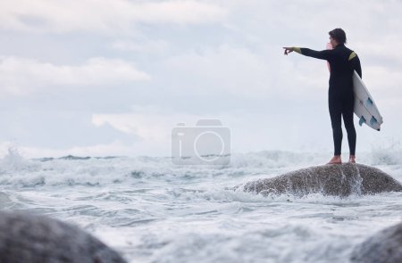 Photo for Man, pointing or surfer on rocks at beach, ocean or rough sea and watching tide, waves or water movement in Hawaii. Sports athlete, surf board or surfing person in fitness, workout or nature training. - Royalty Free Image