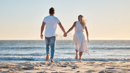 Photo for Couple, hand holding and vacation at beach, love and trust together with travel and adventure with nature and ocean view. Man, woman bonding and back view, support with sea, sand and romantic holiday. - Royalty Free Image