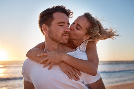 Love, couple and cheek kiss at beach on date, vacation or summer trip. Sunset, affection or romance of man and woman kissing at seashore, bonding and enjoying quality time together outdoors at coast