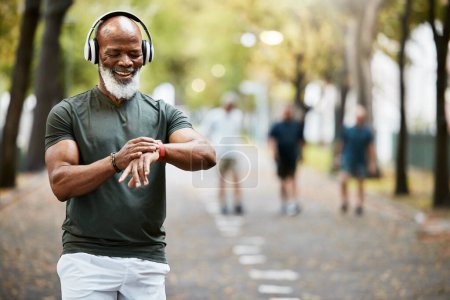 Photo for Music, time and running with a mature black man looking at his watch while out for a fitness run in the park. Workout, wellness and training with a senior male athlete or runner tracking his health. - Royalty Free Image