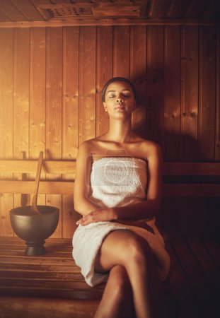 Téléchargez les photos : Assis dans le sauna. une jeune femme se relaxant dans le sauna d'un spa - en image libre de droit
