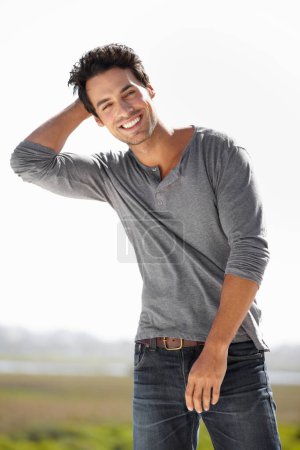 Hes got a laid-back personality. Portrait of a handsome young man standing outside with his hand on his head