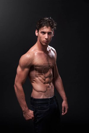 I like my muscles lean and mean. Studio shot of a handsome bare-chested young athlete standing against a black background