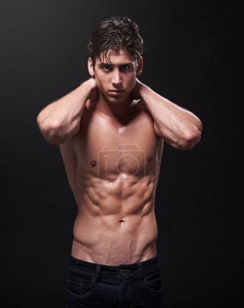 My body is a reflection of my lifestyle. Studio shot of a handsome bare-chested young athlete standing against a black background