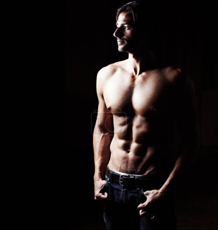 Sculpted to perfection. Low-key image of a muscular young man on a black background