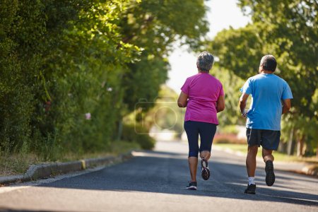 Photo for Keeping their feet moving through retirement. Rearview shot of a mature couple jogging together on a sunny day - Royalty Free Image
