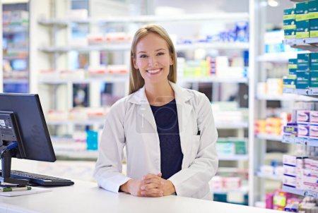 Foto de ¿Cómo puedo ayudar? Retrato de un farmacéutico atractivo de pie en el mostrador de prescripción - Imagen libre de derechos