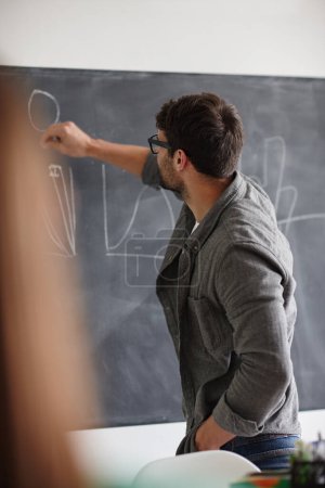 Photo for Presenting his welll-studied statistics. a young man writing information on a blackboard - Royalty Free Image