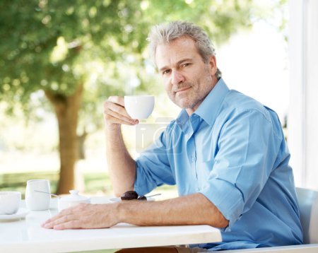 Nehmen Sie sich eine Auszeit, um sich zu entspannen. Glücklich reifer Mann genießt eine Tasse Kaffee im Freien