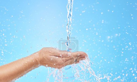 Photo for Hand, water and cleaning with a splash in studio on a blue background for hygiene or hydration. Mockup, health and wellness with a female washing under a water splash in the bathroom for skincare. - Royalty Free Image