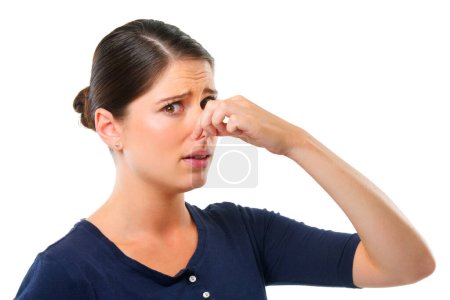 Gross. Studio shot of a young woman holding her nose isolated on white